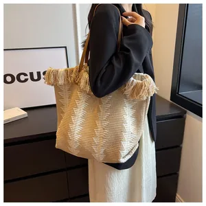 Detail der Boho-Strick-Tragetasche mit Quastenverzierung und geometrischem Muster