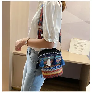 Dettaglio della borsa a secchiello intrecciata con nappe blu e motivi etnici sulla tracolla