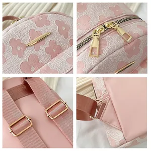 Front view of pink floral backpack with gold plaque and dual metal zipper detail