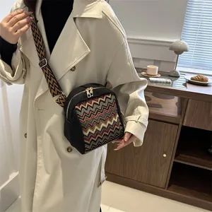 Lifestyle shot of an ethnic patterned crossbody bag with colorful woven straps and gold zippers