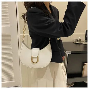 Lifestyle shot of a woman wearing a white crescent shoulder bag with golden chain detail