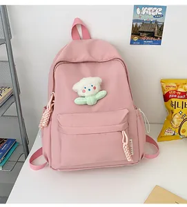Gros plan du sac à dos rose clair avec charm d'ours blanc et poche avant zippée