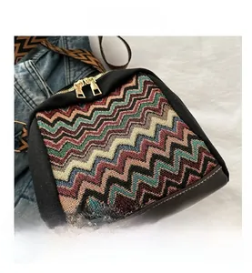 Detail view of ethnic knit crossbody bag with wave patterns and wide woven strap