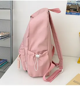 Vue détaillée latérale d'un sac à dos en nylon rose avec poche à cordon et breloque