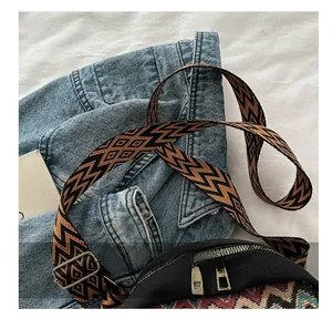 Close-up of wide geometric woven shoulder strap and black canvas bag with metal buckles