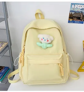 Détail du sac à dos scolaire jaune clair avec pendentif fleur dans un décor lifestyle