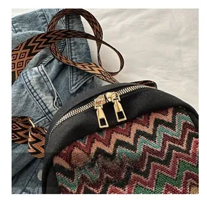 Close-up of golden smooth metal zippers and colorful chevron embroidery on canvas bag