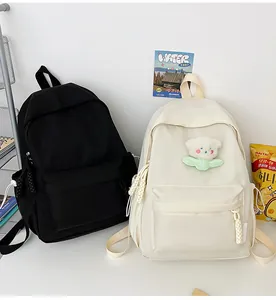 Détail de sacs à dos minimalistes en toile noir et beige avec ornement d'ours mignon