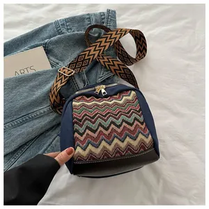 Detail of retro crossbody bag with colorful knit pattern and wide woven strap on bed