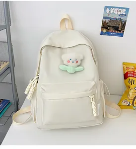 Détail d'un sac à dos blanc cassé avec pendentif ours mignon et tirettes de fermeture tressées