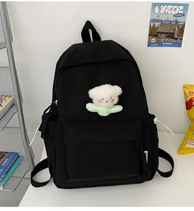 Détail d'un sac à dos en toile noire avec pendentif fleur en peluche et poche latérale