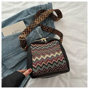 Detail of ethnic crossbody bag with colorful woven patterns and wide geometric strap