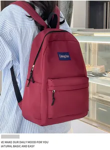 Detailansicht des weinroten minimalistischen Rucksacks mit Logo und großen Seitentaschen