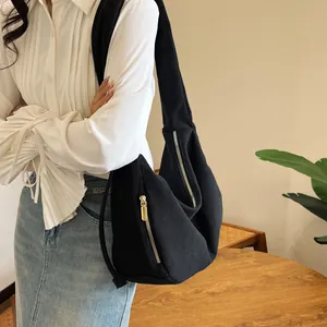 Detail of black corduroy shoulder bag showing vertical rib texture and gold zipper