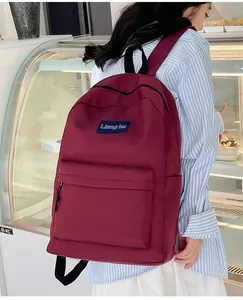 Detail eines burgunderroten Nylon-Rucksacks mit Fronttasche und Markenetikett-Ansicht