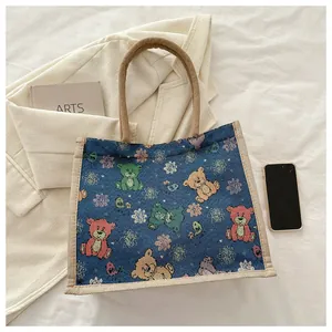 Détail de la texture d'un sac cabas en lin bleu avec motif d'ours et poignée tressée