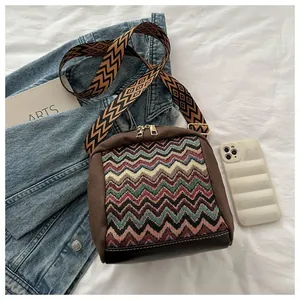 Detail of colorful zigzag woven bag with wide patterned strap and dual zippers