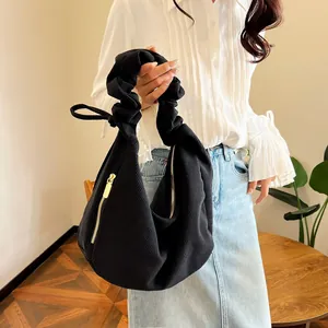 Detail of black corduroy bag with gold zipper and stylish pleated handle textures