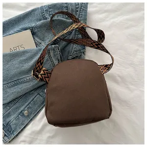 Detail of deep brown canvas crossbody bag with geometric pattern woven wide shoulder strap