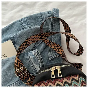 Close-up of ethnic geometric jacquard fabric with gold dual zippers and wide shoulder strap
