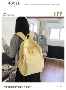 Detail of light yellow canvas backpack with woven zipper pulls worn by model in a bright room