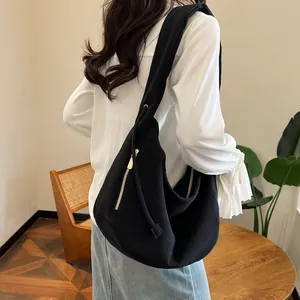 Detail of black corduroy shoulder bag with gold zipper and textured hobo style fabric