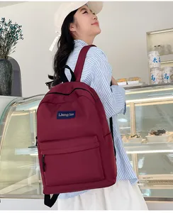 Seitenansicht eines burgunderroten minimalistischen Rucksacks mit Logo-Patch im Lifestyle