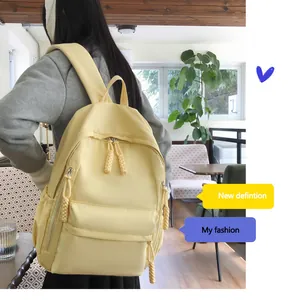 Detail of yellow nylon backpack featuring braided zipper pulls and side pockets