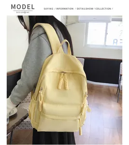 Detail of light yellow nylon backpack showing woven zipper pulls and front pocket texture