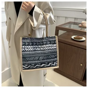 Detail of bohemian burlap tote bag with ethnic geometric patterns and woven handles