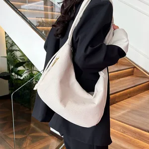 Detail view of cream corduroy shoulder bag showing texture and golden zipper
