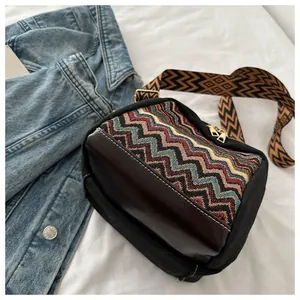 Close-up of bohemian small square bag with multi-color woven pattern and leather base