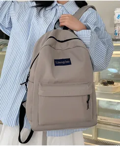 Detailansicht eines beigen Nylon-Rucksacks mit Markenlabel und Fronttasche