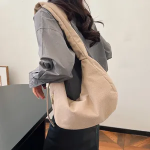 Detail of beige corduroy hobo bag showing ribbed texture and golden zipper accents