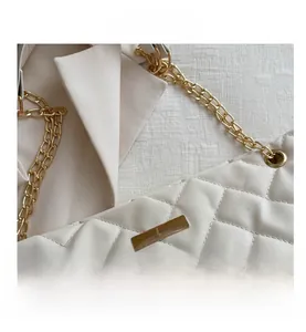 Macro detail of white quilted PU leather tote featuring a gold chain and metal lock