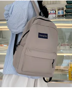 Detailansicht des beigen minimalistischen Rucksacks mit Logo-Patch und Reißverschlusstasche