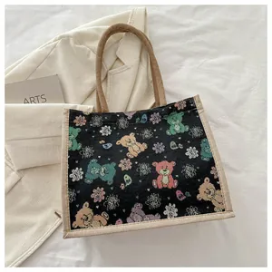 Détail d'un sac cabas tissé noir avec broderie d'ours en dessin animé et fleurs