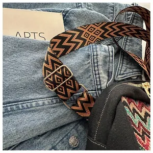 Close-up of bohemian style woven bag strap with geometric patterns and gold metal buckles