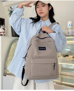 Detail eines khakifarbenen Nylon-Rucksacks mit Reißverschlusstasche und Markenetikett