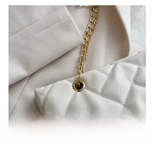 Close-up of beige quilted tote bag with gold chain strap and metal eyelet details
