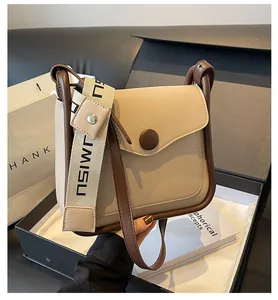 Dettaglio borsa a tracolla bicolore beige e marrone con ampia tracolla logata