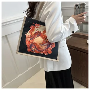 Detail of black canvas tote bag featuring a red dragon totem print on a minimalist model