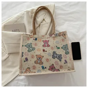 Vue détaillée de dessus d'un sac cabas en toile tissée avec des ours et des oiseaux colorés