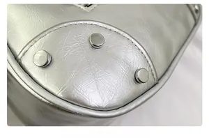Close-up of bottom metal studs and wrinkled silver leather texture on a crossbody bag