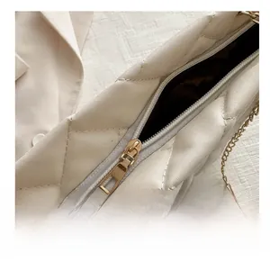 Detail of smooth gold zipper and quilted pattern on white leather tote bag