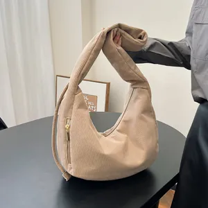 Detail of beige corduroy shoulder bag showing ribbed texture and gold zipper