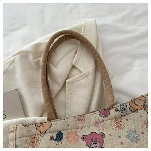 Détail d'un sac cabas tissé avec motifs d'ours mignons et anses en corde marron