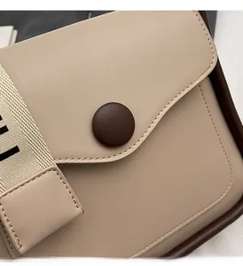 Dettaglio borsa beige in pelle PU con fibbia marrone e tracolla in tessuto strutturato
