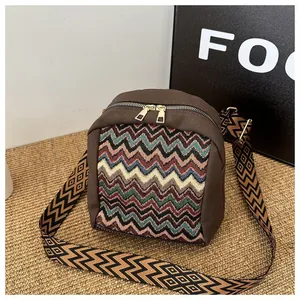 Detailed view of colorful chevron knit patterns and dual gold zippers on a canvas bag