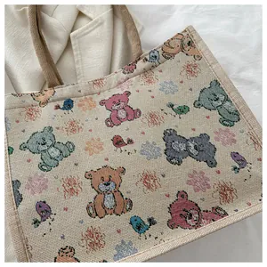 Détail d'un cabas tissé avec motifs d'ours colorés et poignées en corde de chanvre